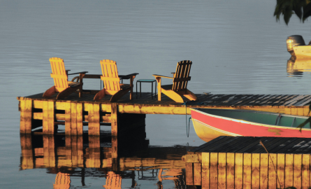 small watercraft at dock, chairs on dock, lake, islands, trees